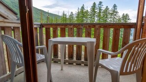 A balcony with a table and two chairs, overlooking a forested area. - 40m from ski slopes, floor -2, fitness, swimming pool, sauna, balcony, tv, ski locker, 31m² (Les Orres)