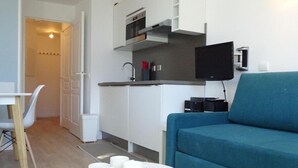 A modern living room with a teal sofa, a dining table with chairs, and a kitchen area with a microwave and a flat-screen TV. - 10m from ski slopes, 5th floor, view mountain, balcony, tv, ski locker, 41m², Avoriaz (Avoriaz)