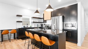 A modern kitchen with a central island, bar stools, stainless steel appliances, and pendant lighting. - Golf Lodge Lake Views Hot Tub Rooftop Arcade (Hollister)