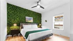 A bedroom with a bed, bedside tables, a green wall, a ceiling fan, and a window with a balcony view. - Golf Lodge Lake Views Hot Tub Rooftop Arcade (Hollister)