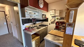 Una cocina compacta con un reloj, un microondas y un lavamanos.