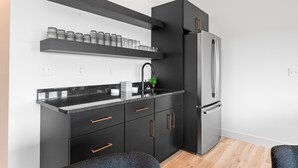 A modern kitchen with black cabinetry, stainless steel appliances, and a granite countertop. - Branson GOAT: Golf Simulator Hot Tub Lake View Fun (Branson)