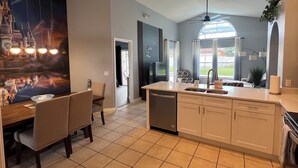 A modern kitchen with a large island, a dining area with chairs, and a mural of a castle. - Disney World Vacation Home (Kissimmee)
