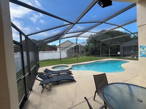A screened outdoor area with a pool, lounge chairs, and a table. - Disney World Vacation Home (Kissimmee)