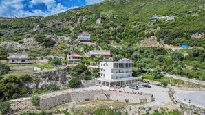 Una propiedad en una ladera con varias construcciones, un camino pavimentado y un muro de piedra.
