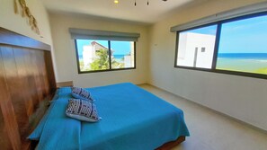 A bedroom with a bed, two pillows, a window with a view of the beach, and a ceiling fan. - Corcomoran Luxury Beachfront house (Telchac Puerto)