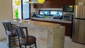 A modern kitchen with granite countertops, stainless steel appliances, and pendant lighting. - Corcomoran Luxury Beachfront house (Telchac Puerto)