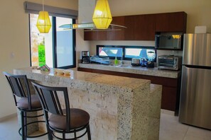 A modern kitchen with granite countertops, stainless steel appliances, and pendant lighting.