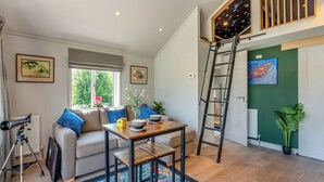 Een moderne woonkamer met een bank, salontafel en een ladder tegen een groene muur.