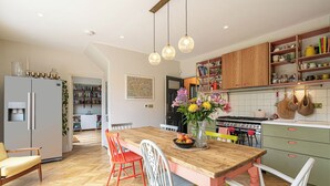 Une cuisine moderne avec un îlot central en bois, un coin repas avec des chaises colorées et un réfrigérateur.