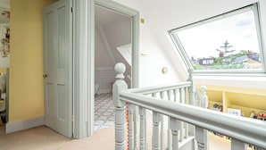 Une pièce avec un escalier menant à l’étage supérieur, une grande fenêtre offrant une belle vue et une porte donnant sur une autre pièce.
