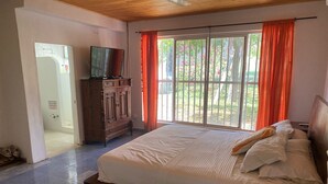 A bedroom with a large bed, a wooden wardrobe, a television, and a window with curtains. - Tahiti Diamond Rest Farm (Girardot)