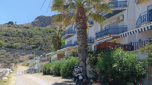 A residential area with a dirt road, a parked motorcycle, and buildings with balconies. - Margarita Ocean View Apartment (Sant'Alessio Siculo)