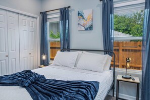 Relax in a serene bedroom with a comfortable bed, bedside table, and window offering a view of the garden.