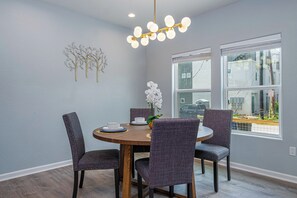 Enjoy meals in this stylish dining area with a round table and comfortable chairs, featuring a unique metal art piece and a large window with a view.