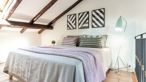 A bedroom with a bed, a floor lamp, and three wall-mounted artworks. - Barbieri23 Design by Wonderful Italy (Bologna)