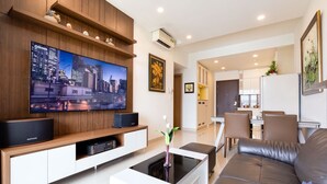 Una sala de estar moderna con televisor de pantalla plana, una mesa de centro, un sofá y un área de comedor al fondo.