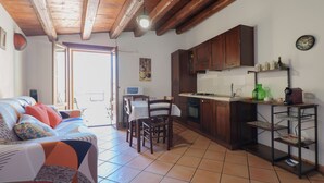 A cozy living room with a sofa and chairs, a kitchen with wooden cabinets and a dining area.