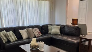 A living room with a black leather sofa, a wooden coffee table, and a ceiling fan.