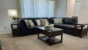 A living room with a sectional sofa, two side tables, a coffee table, and a lamp.
