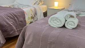 A hotel room with two beds, each with a distinct patterned bedspread.