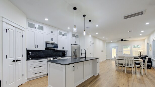 Una cocina moderna con armarios blancos, una isla central e iluminación colgante.