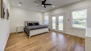 Un dormitorio con cama, ventilador de techo, mesita de noche y ventana.