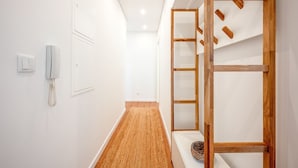A modern hallway with a wooden bench, a phone, and a wall-mounted shelf. - GuestReady - Bright escape near Santa Apolónia (Lisbon)