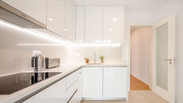 A modern kitchen with white cabinets, a black countertop, a Bosch coffee maker, and a toaster. - GuestReady - Bright escape near Santa Apolónia (Lisbon)