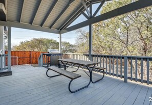 Une terrasse extérieure couverte, équipée d’une table de pique-nique et d’un barbecue.