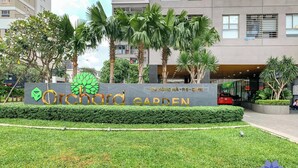 Señal de Orchard Garden con un edificio moderno al fondo.