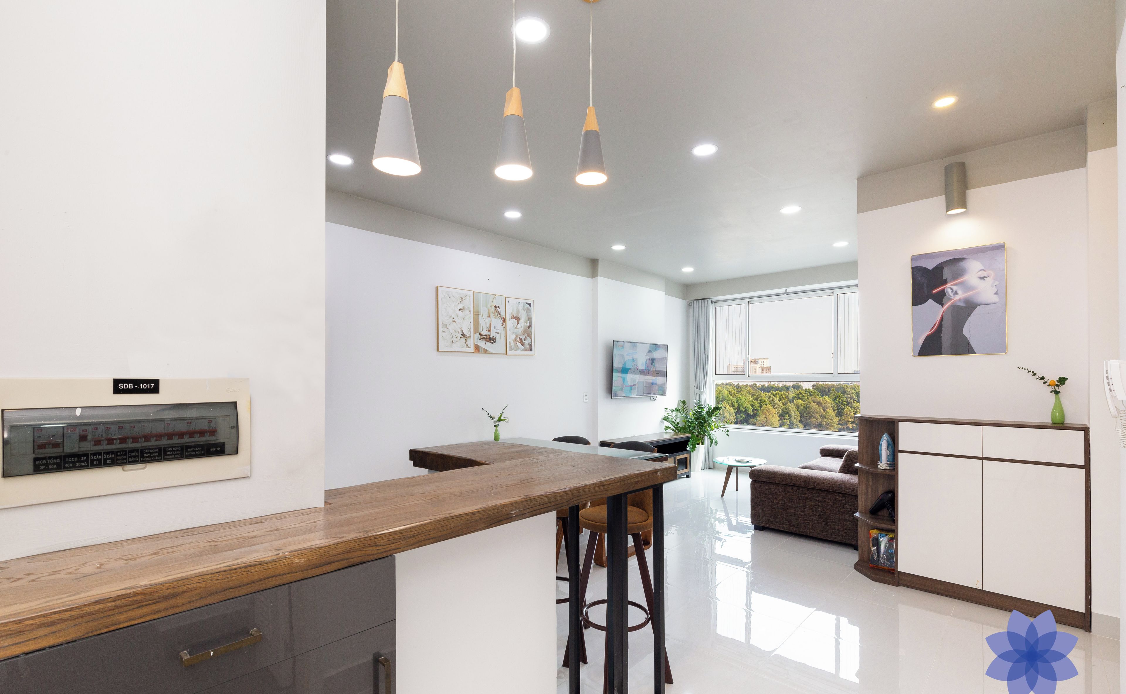 A modern kitchen with a wooden countertop, bar stools, pendant lights, and a built-in oven.
