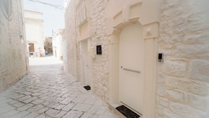 A narrow cobblestone street flanked by white stone buildings with a closed door and a small window. - Cinquanta Sfumature B&b Luxury Suites (Cassano delle Murge)