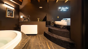 A modern bathroom with a freestanding bathtub, a small seating area, and a staircase leading to a bedroom. - Cinquanta Sfumature B&b Luxury Suites (Cassano delle Murge)