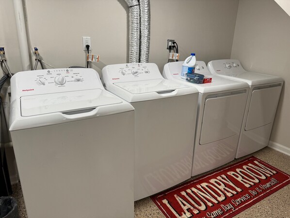 A laundry room with three stacked washing machines, a water heater, and a detergent bottle. - Hot Stuff! Pro Cleaned Self Check In Sleeps 10 (Racine)
