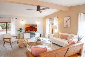 Un salon comprenant un canapé, un fauteuil, une table basse, un téléviseur et un ventilateur de plafond.