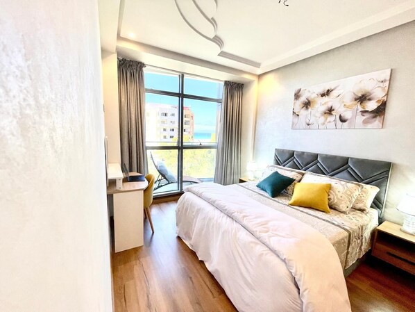 A modern hotel room with a large bed, a desk, and a chair. - Modern Tangier centre elegance with Seaview - Steps to Beach, train, attractions (Tangier)