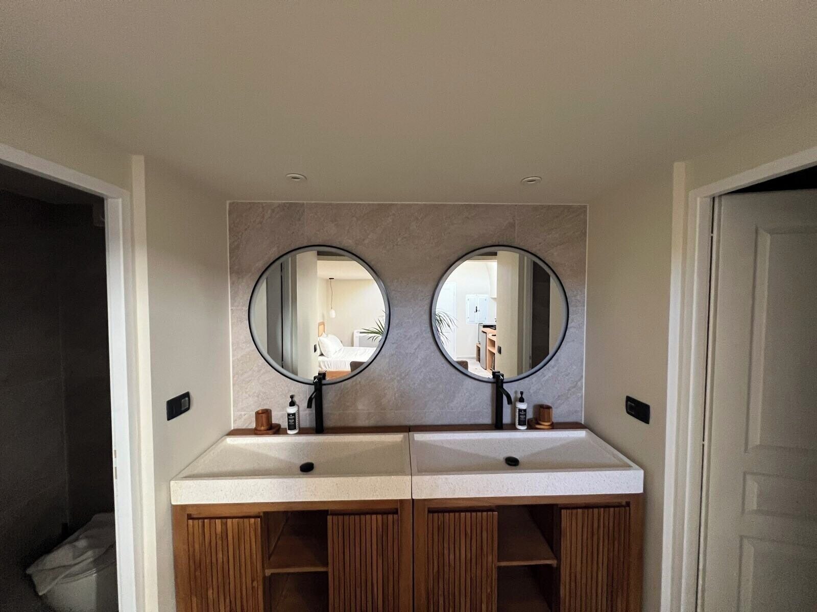 A bathroom with two sinks, wooden cabinets, and round mirrors.