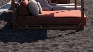 A beachside lounge area with wooden loungers and umbrellas, overlooking the sea. - Casa Frati Suites & Villas (Santorini)