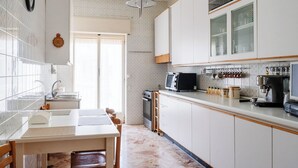 A modern kitchen with white cabinets, a microwave, a coffee maker, and a sink.