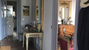 A hallway with a tiled floor, a table with decorative items, a mirror, and a chair. - House in Beaujolais village (Régnié-Durette)