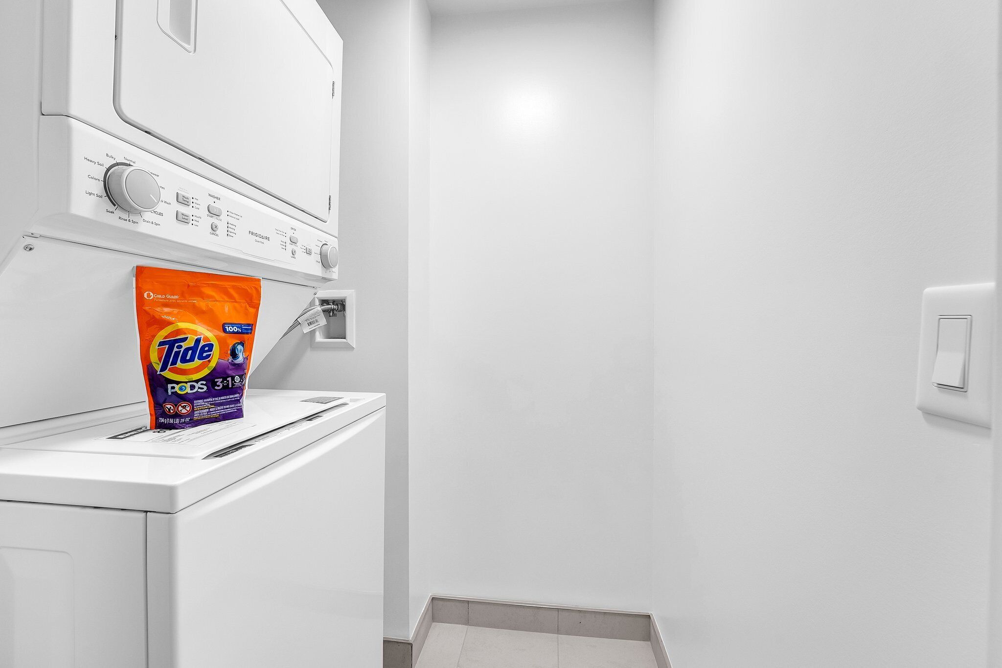 Un área de lavandería con Tide PODS 3-1-19 sobre una lavadora.