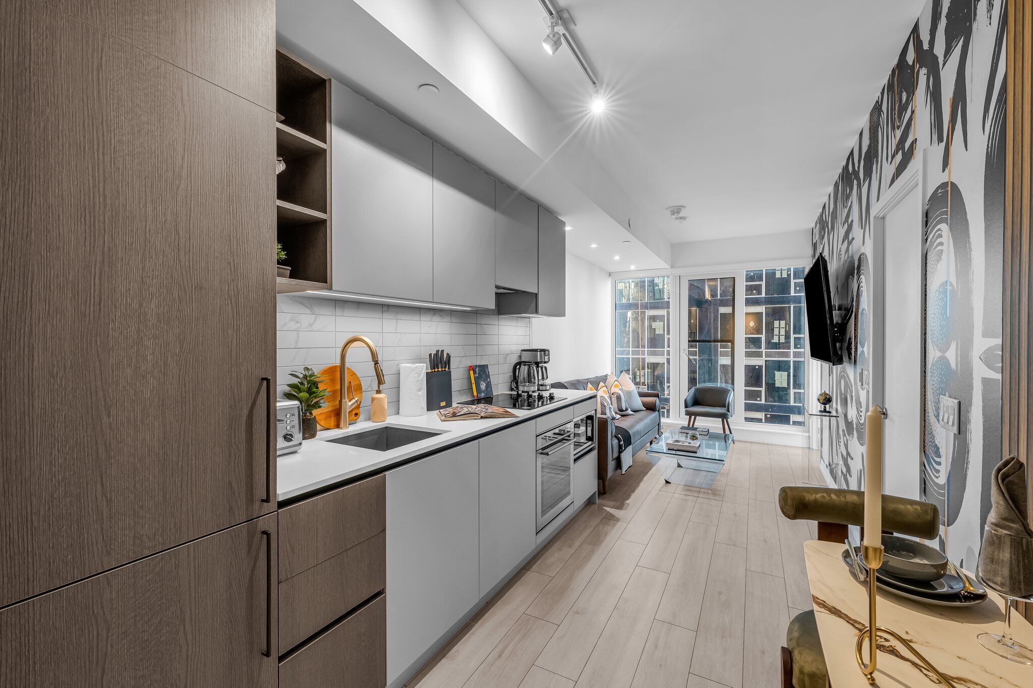A modern kitchen with grey cabinets, a white countertop, and a dining area with a table and chairs.