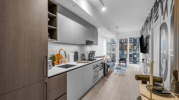 A modern kitchen with grey cabinets, a white countertop, and a dining area with a table and chairs.
