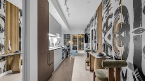 A modern kitchen with a central island, wooden cabinets, and a dining area with a table and chairs. - The Aurelien Luxe Collection (Toronto)