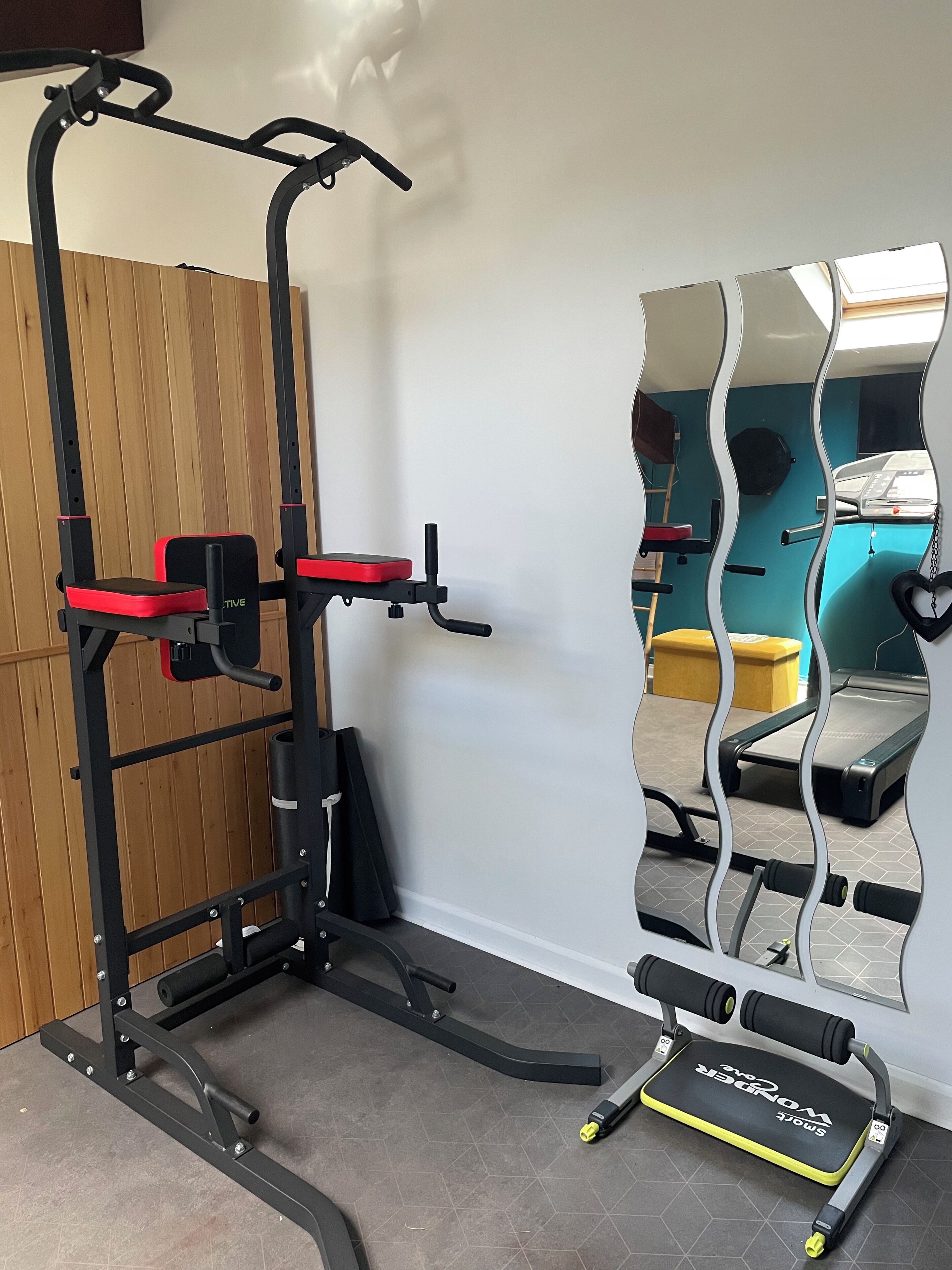 A gym with a pull-up bar, a bench, and a mirror.