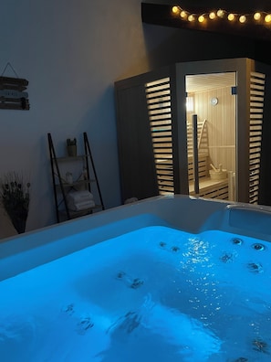 A spa area with a hot tub, wooden walls, and a small entrance to a sauna. - La Samorienne Tiny House, with a private spa and sauna. (Réjaumont)
