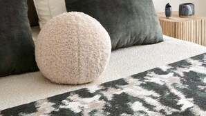 Et pænt indrettet soveværelse med seng, puder, et rundt pled og en hængende lampe.