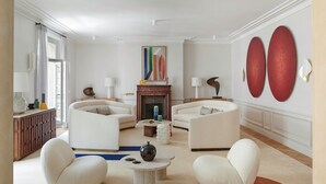 En moderne stue med pejs, to hvide sofaer, et sofabord og abstrakt vægkunst.