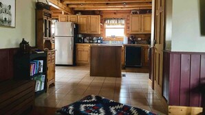 A kitchen with wooden cabinets, a central island, and a refrigerator. - Cozy Fishing and Get-A-Way Cabin minutes from Lake George (Kattskill Bay)